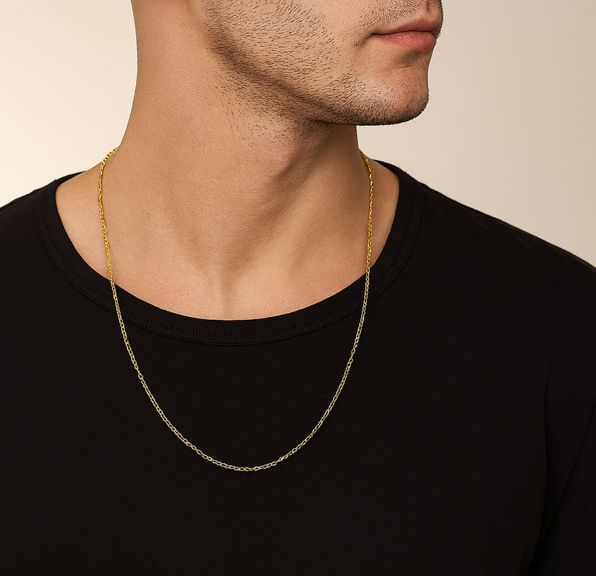 Man wearing a black t-shirt and gold chain necklace against a beige background