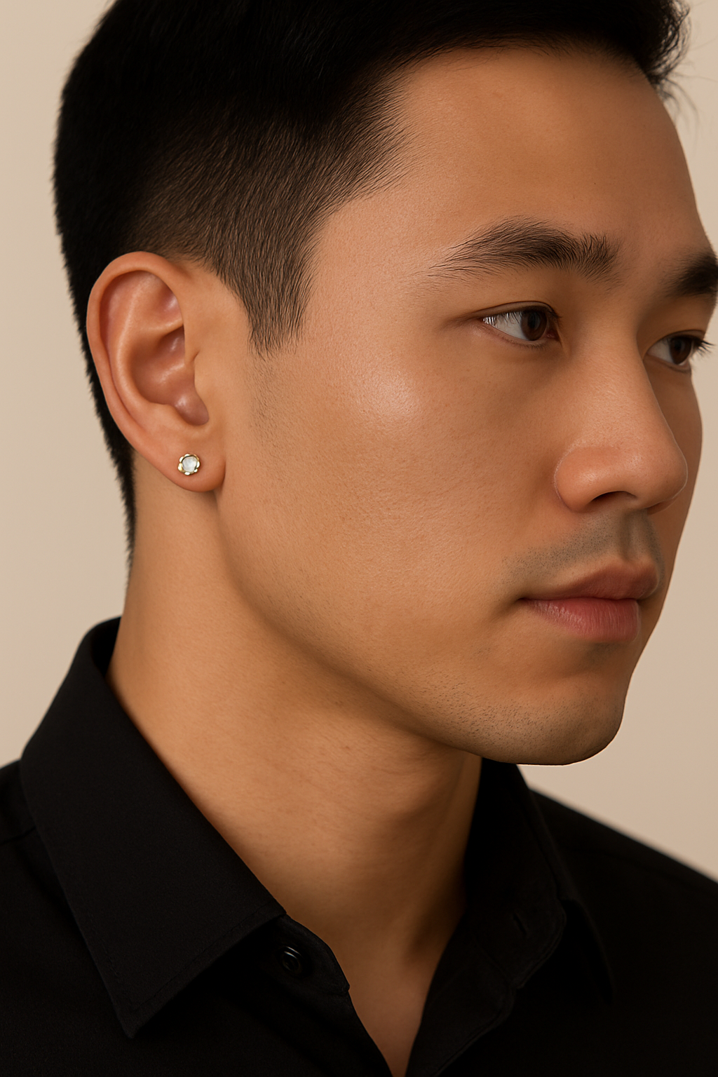 Close-up of a man wearing a diamond earring against a neutral background