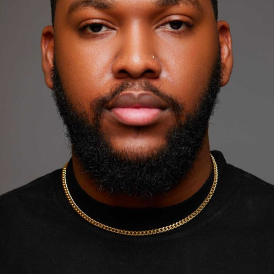 Man wearing a black shirt and gold chain with a gray background
