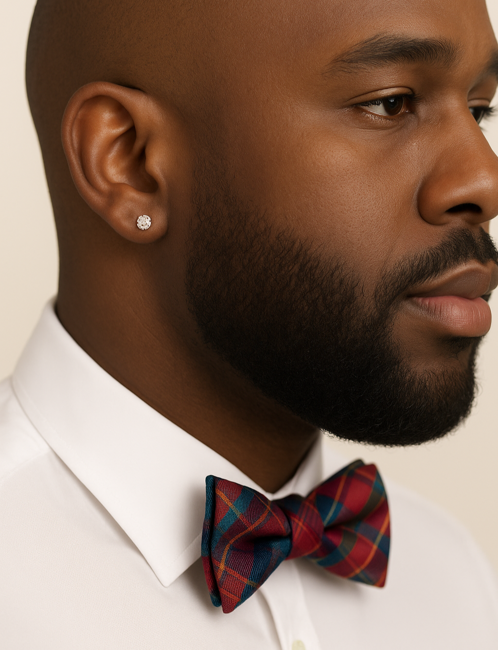 Man wearing a white shirt and red plaid bow tie with a neutral background