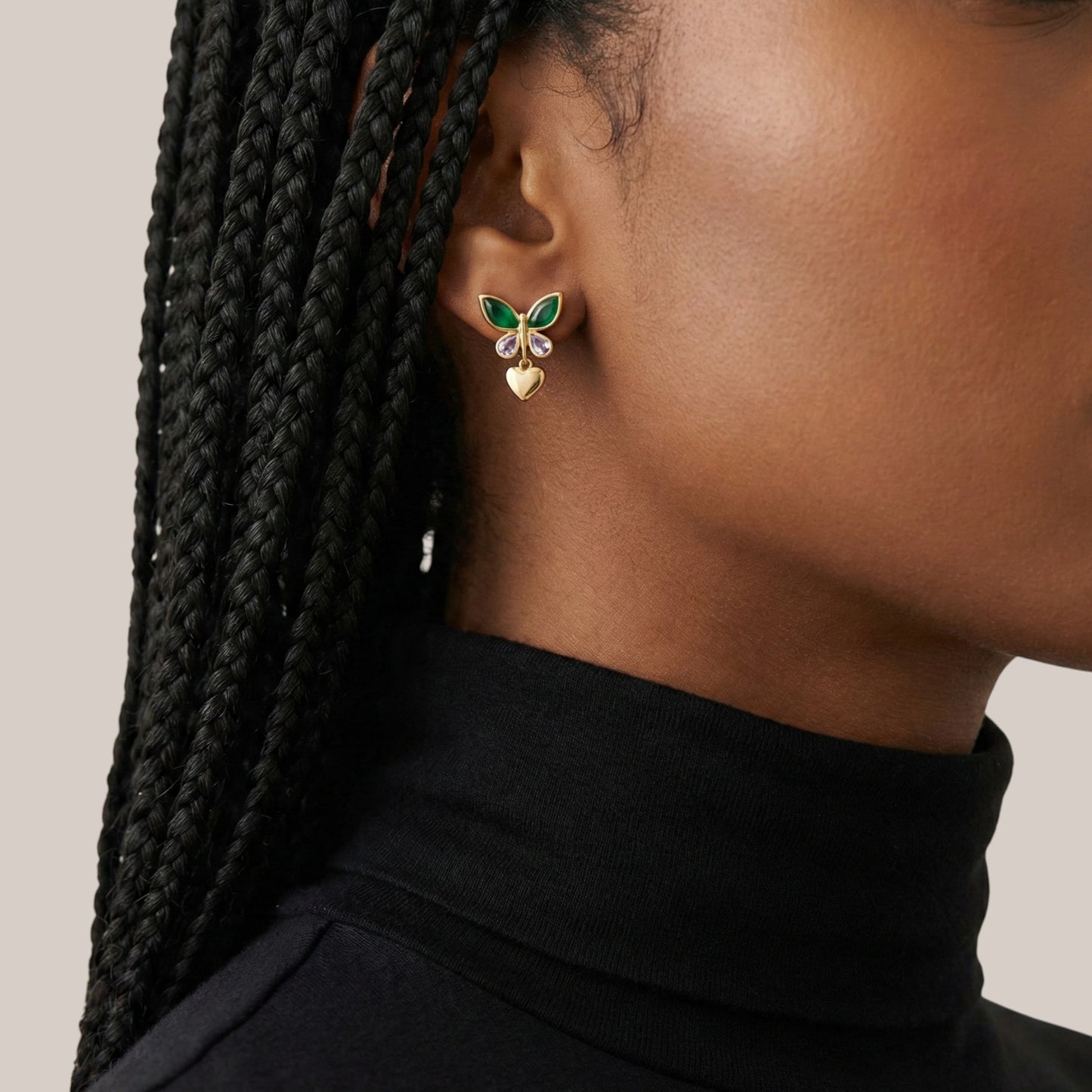 Close-up of a person wearing a butterfly-shaped earring with green and gold details.