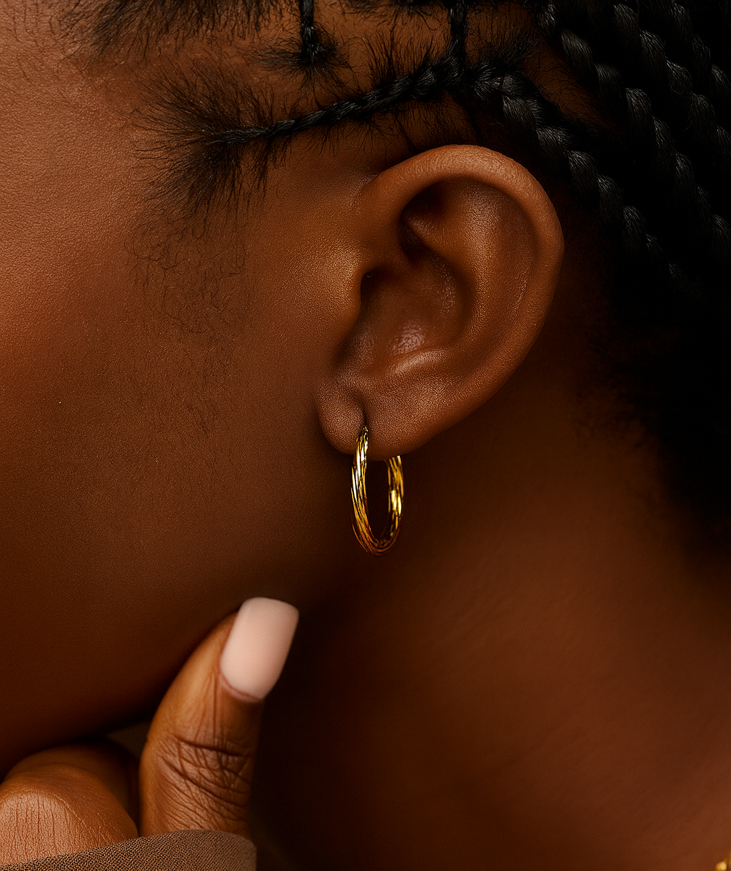 Close-up of an ear wearing a gold hoop earring with a blurred background