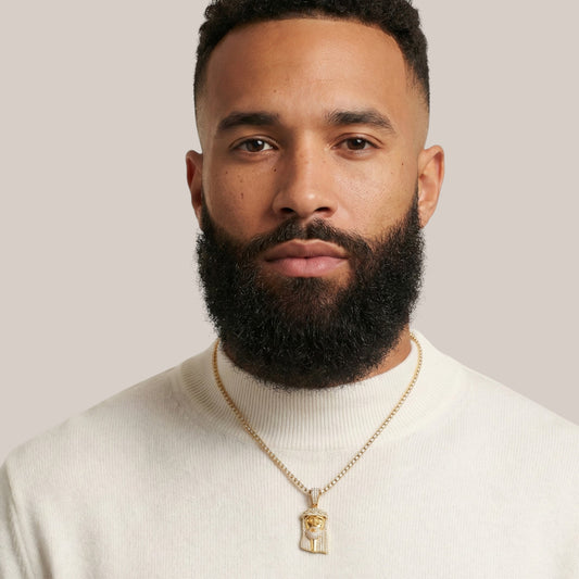 Man wearing a gold necklace with a pendant against a plain background