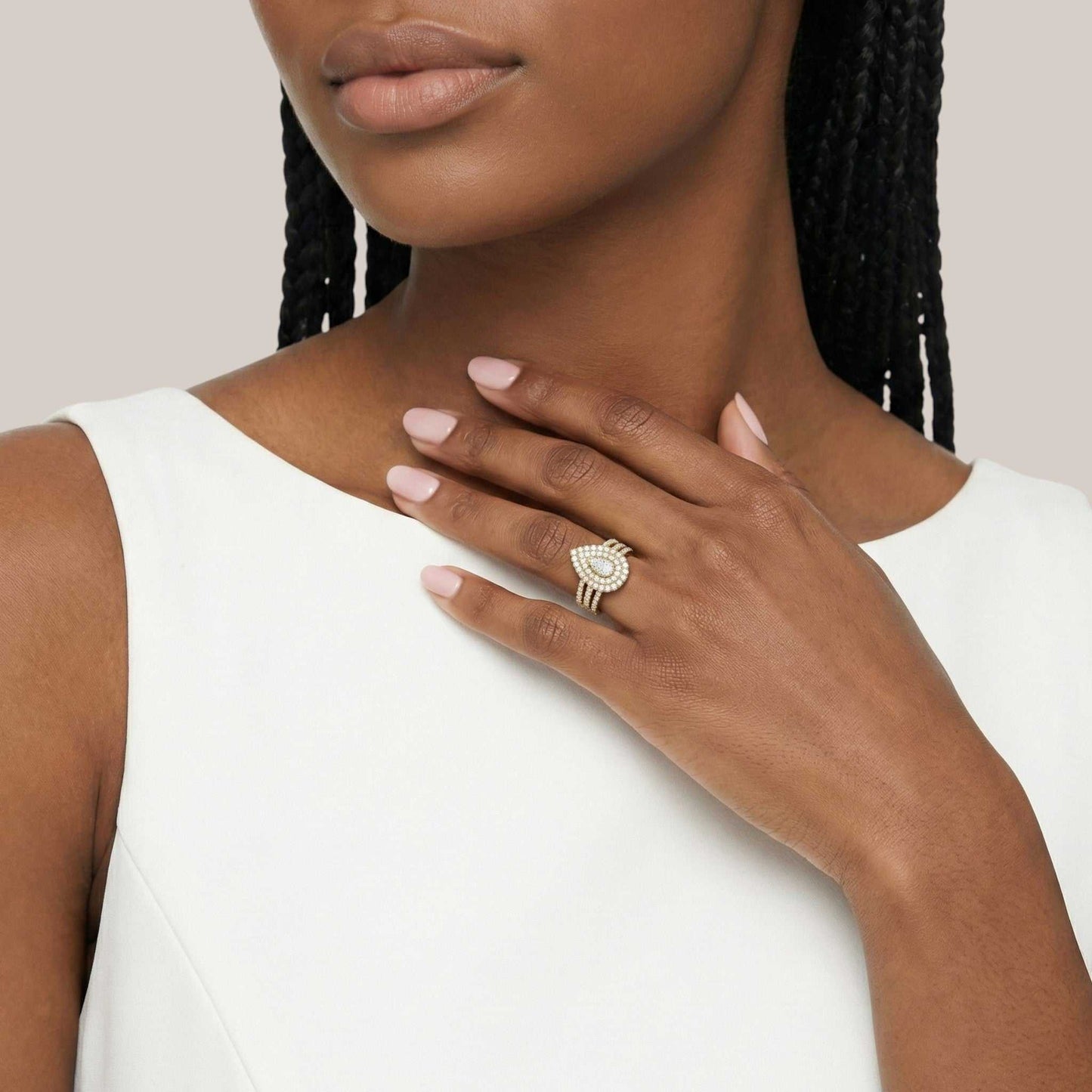 Woman wearing a gold ring with a large diamond on a plain background