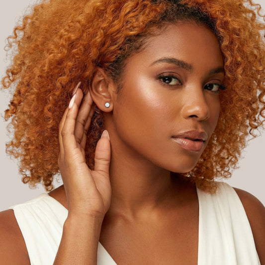 Woman with curly hair wearing a white top against a neutral background