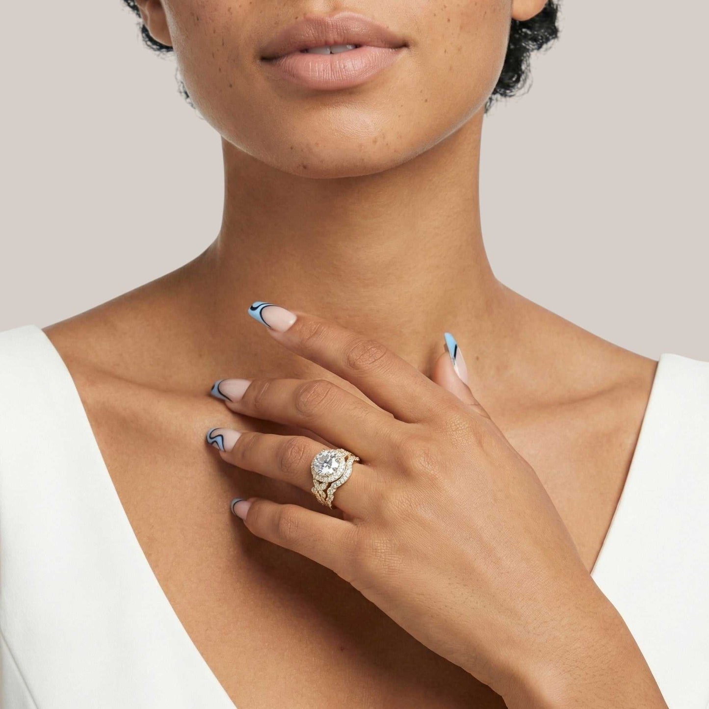 Close-up of a woman's hand wearing a ring with a large diamond, against a neutral background.