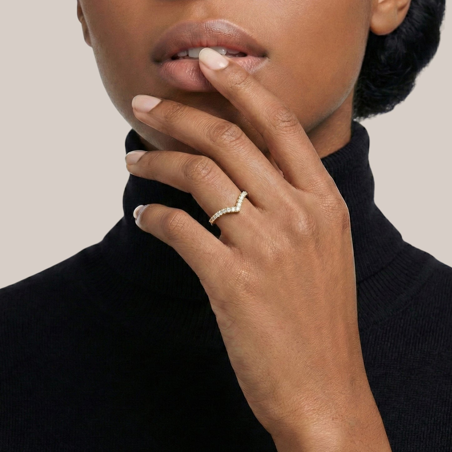 Person wearing a ring with a diamond on a neutral background