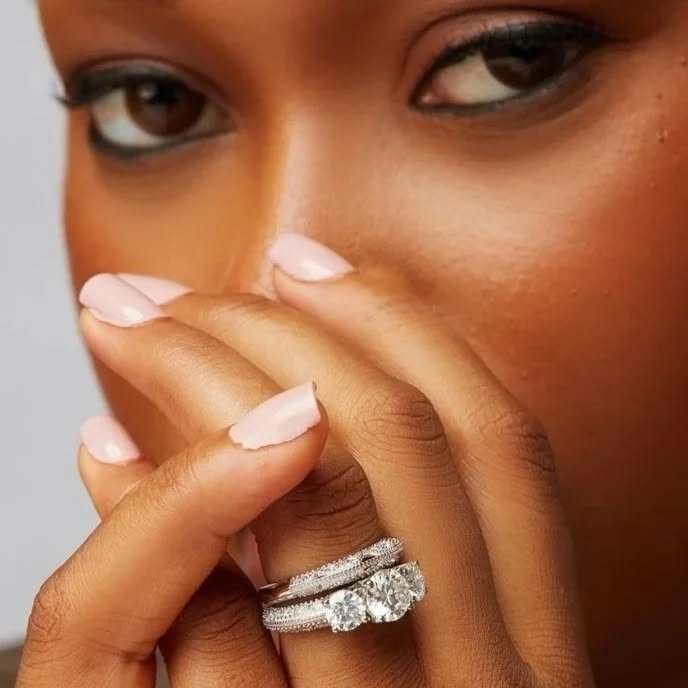 Close-up of Abby Moissanite Bride Set in 925 sterling silver with three-stone moissanite engagement ring and matching wedding band on hand