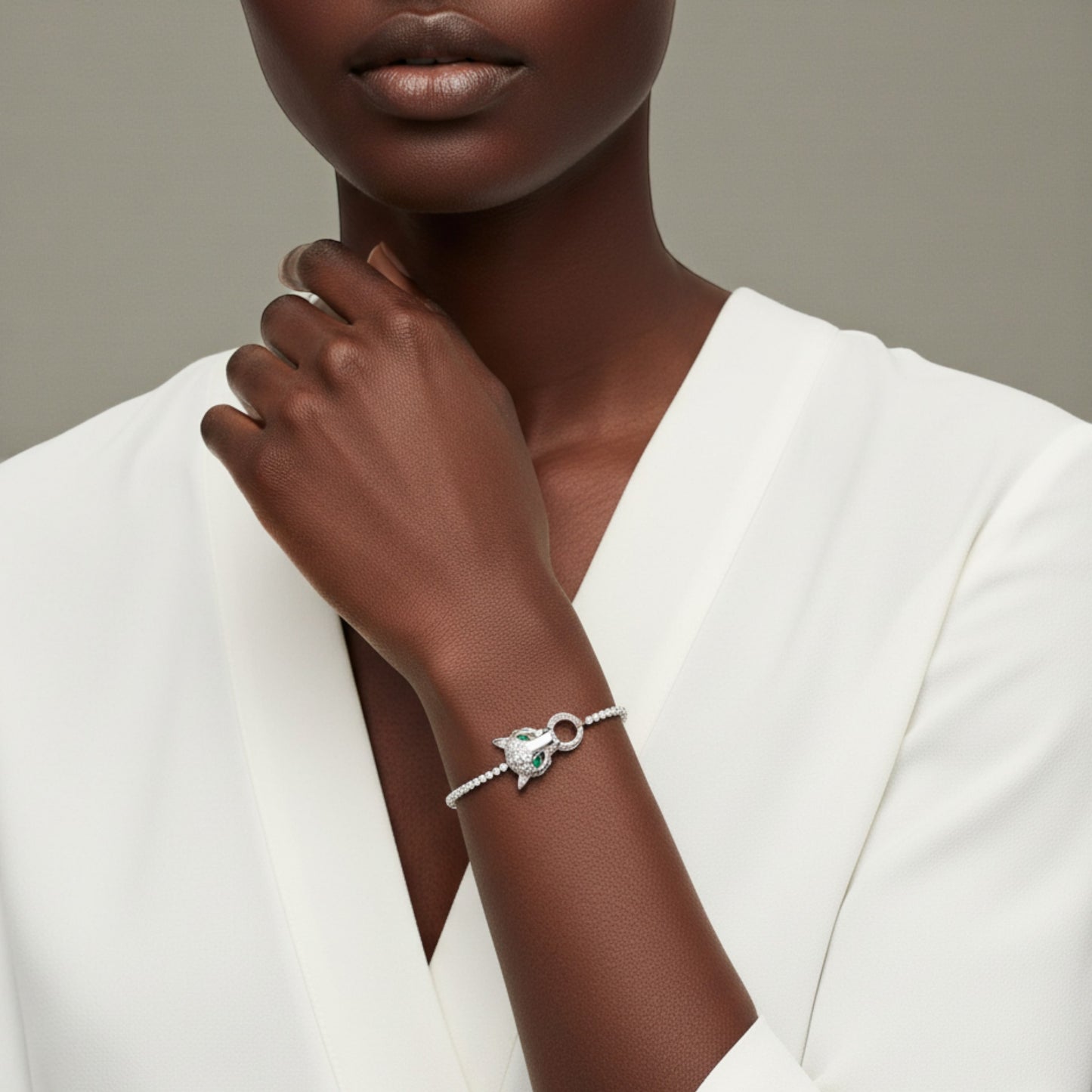 Woman wearing a silver bracelet with a green gemstone on a neutral background