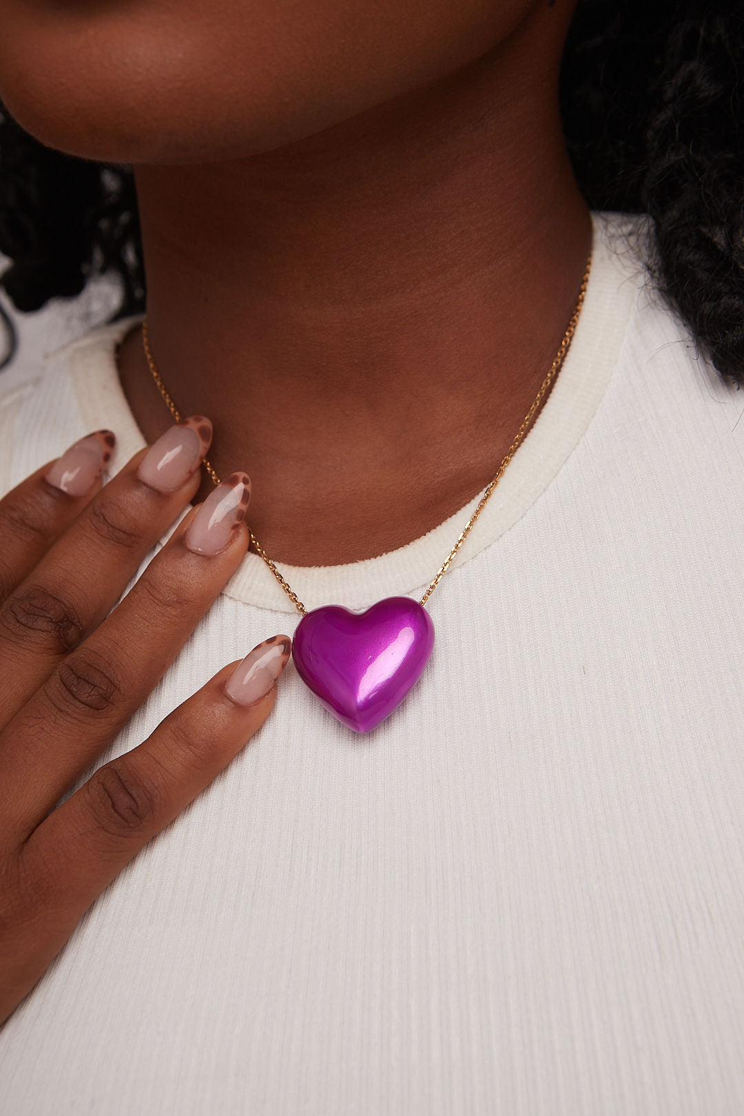 Person wearing a gold necklace with a purple heart pendant