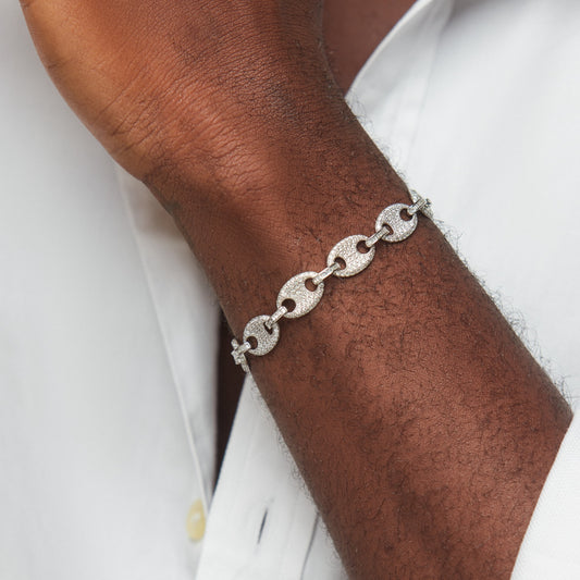 Silver chain bracelet on a wrist with a white shirt background