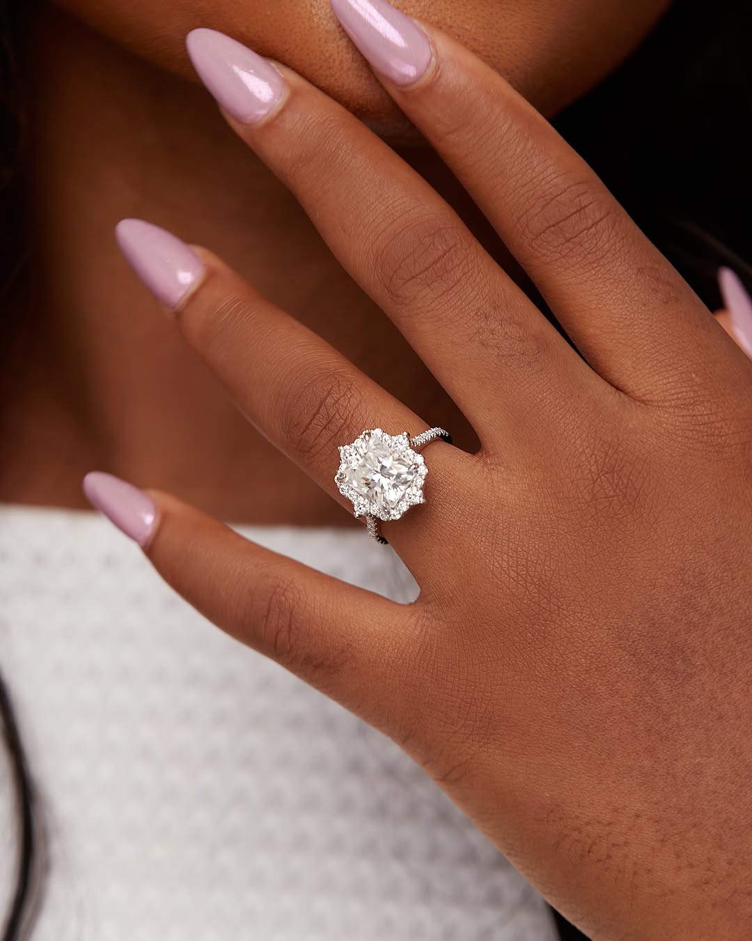 A person's hand displaying a radiant cut moissanite engagement ring on a sterling silver band