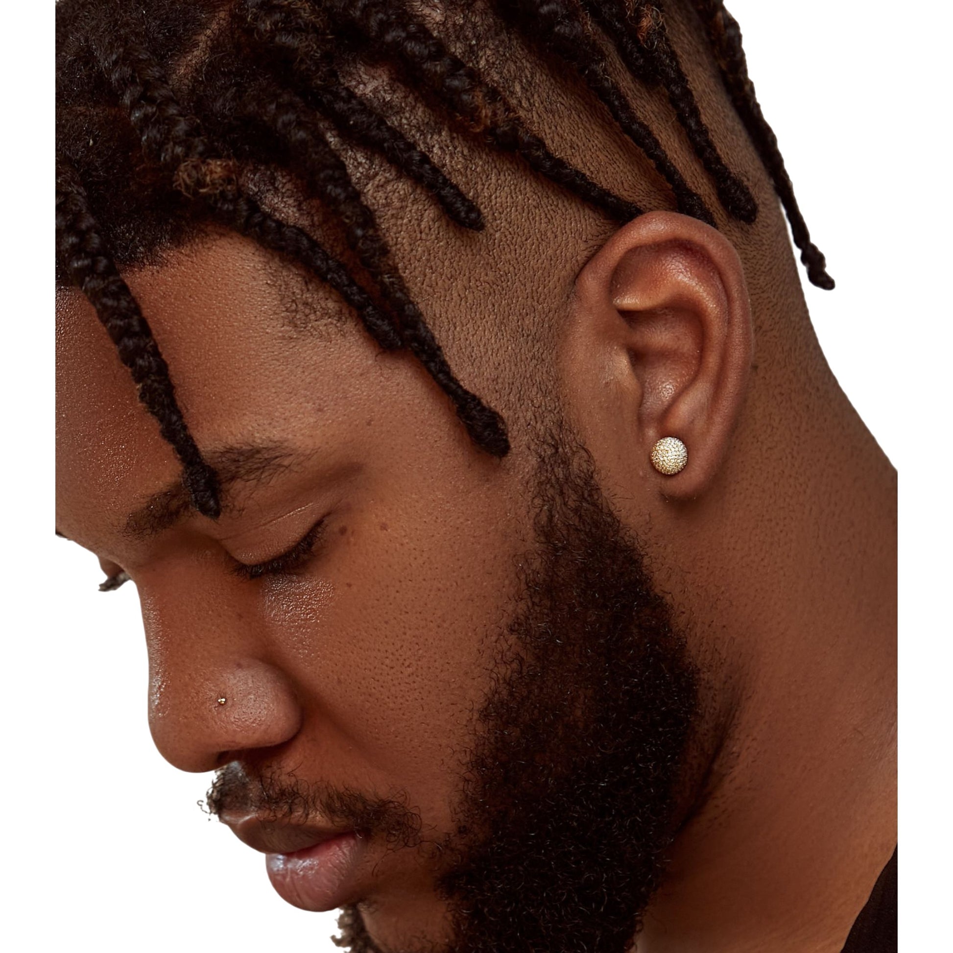 Close-up of a man with braided hair wearing a gold earring on a white background