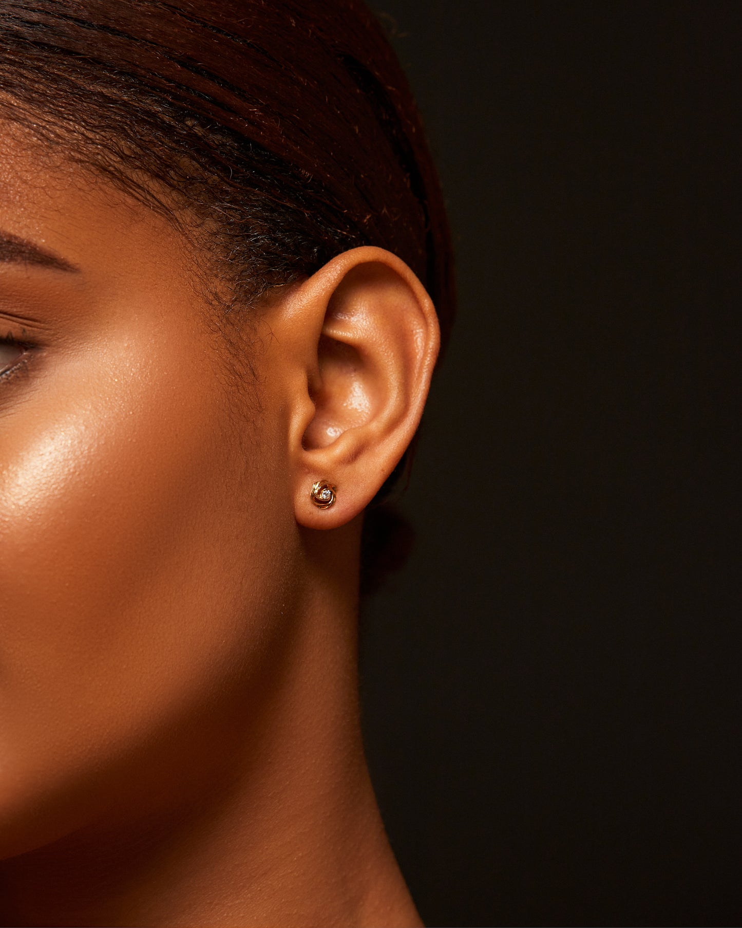 Close-up of a person's ear with an earring against a dark background