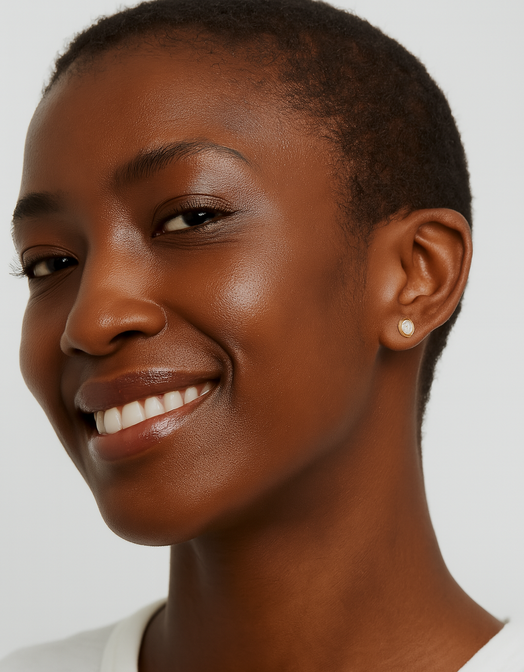 Woman with a short haircut wearing a white shirt against a plain background