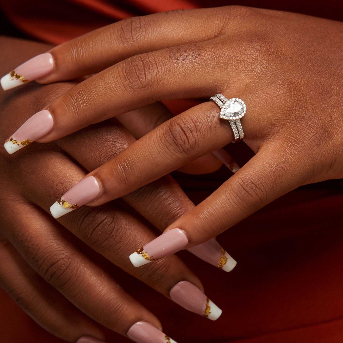Hand wearing a diamond ring with pink nail polish