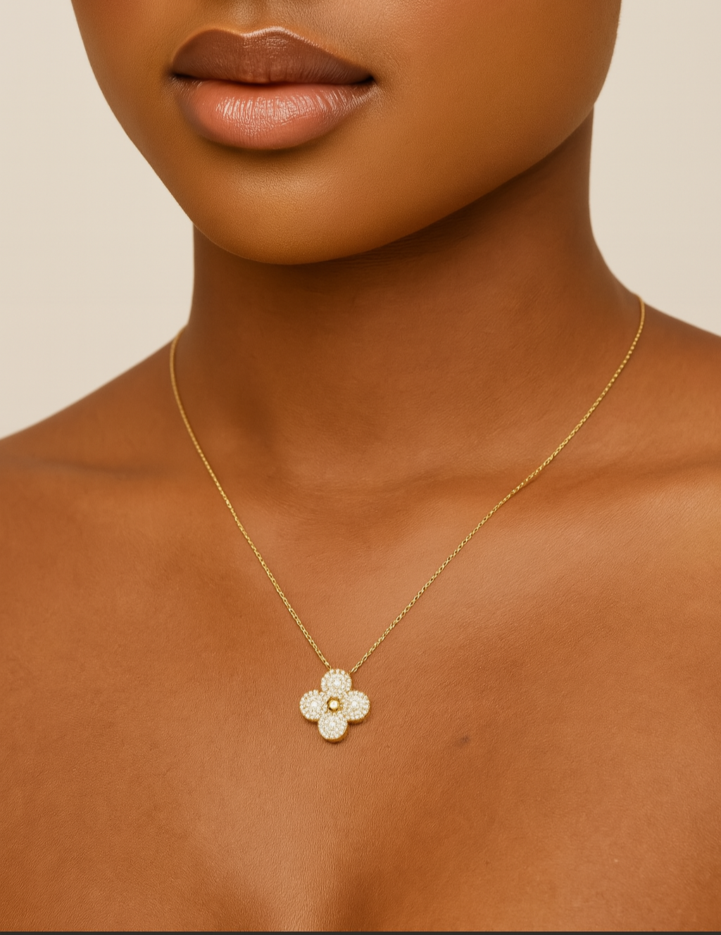 Close-up of a woman wearing a gold necklace with a flower pendant on a beige background