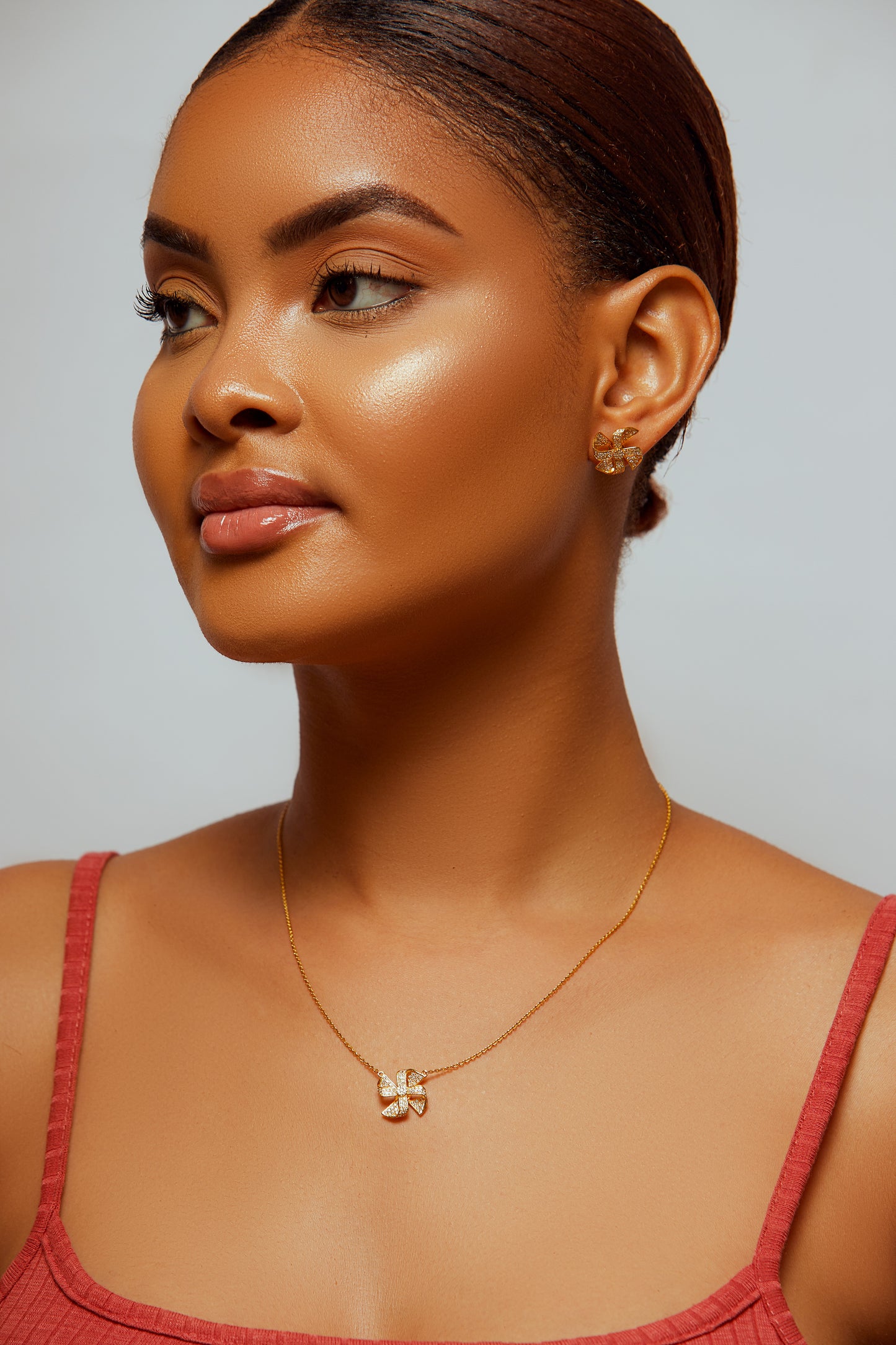 Woman wearing a gold necklace with a pendant against a neutral background