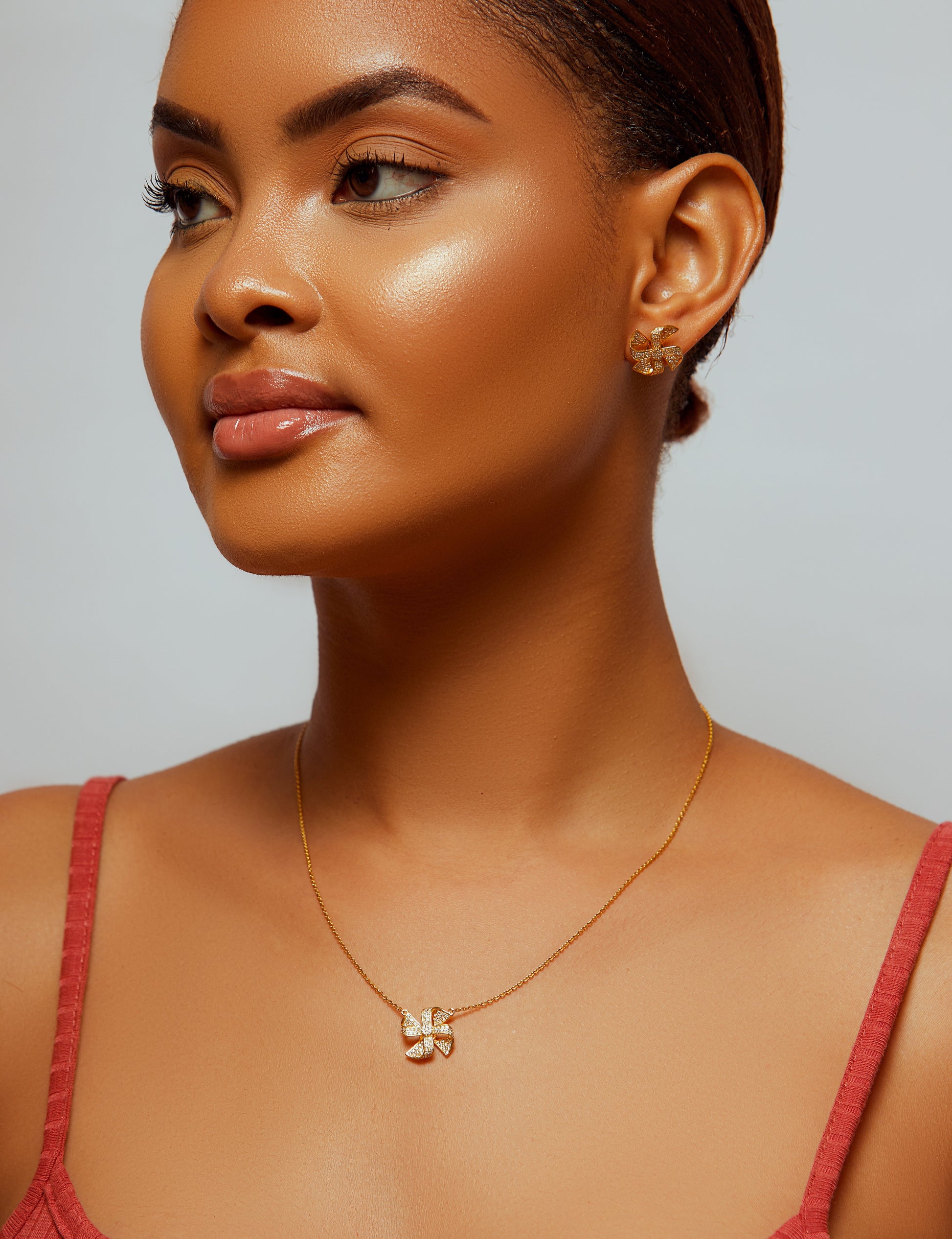 Woman wearing a gold necklace with a pendant against a neutral background