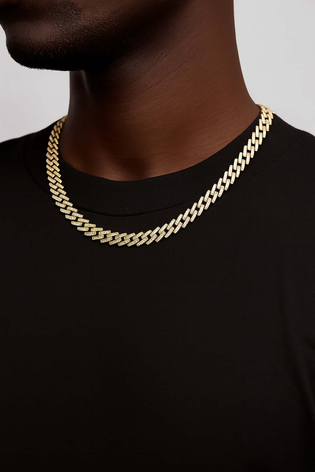 Gold chain necklace on a person wearing a black shirt against a gray background