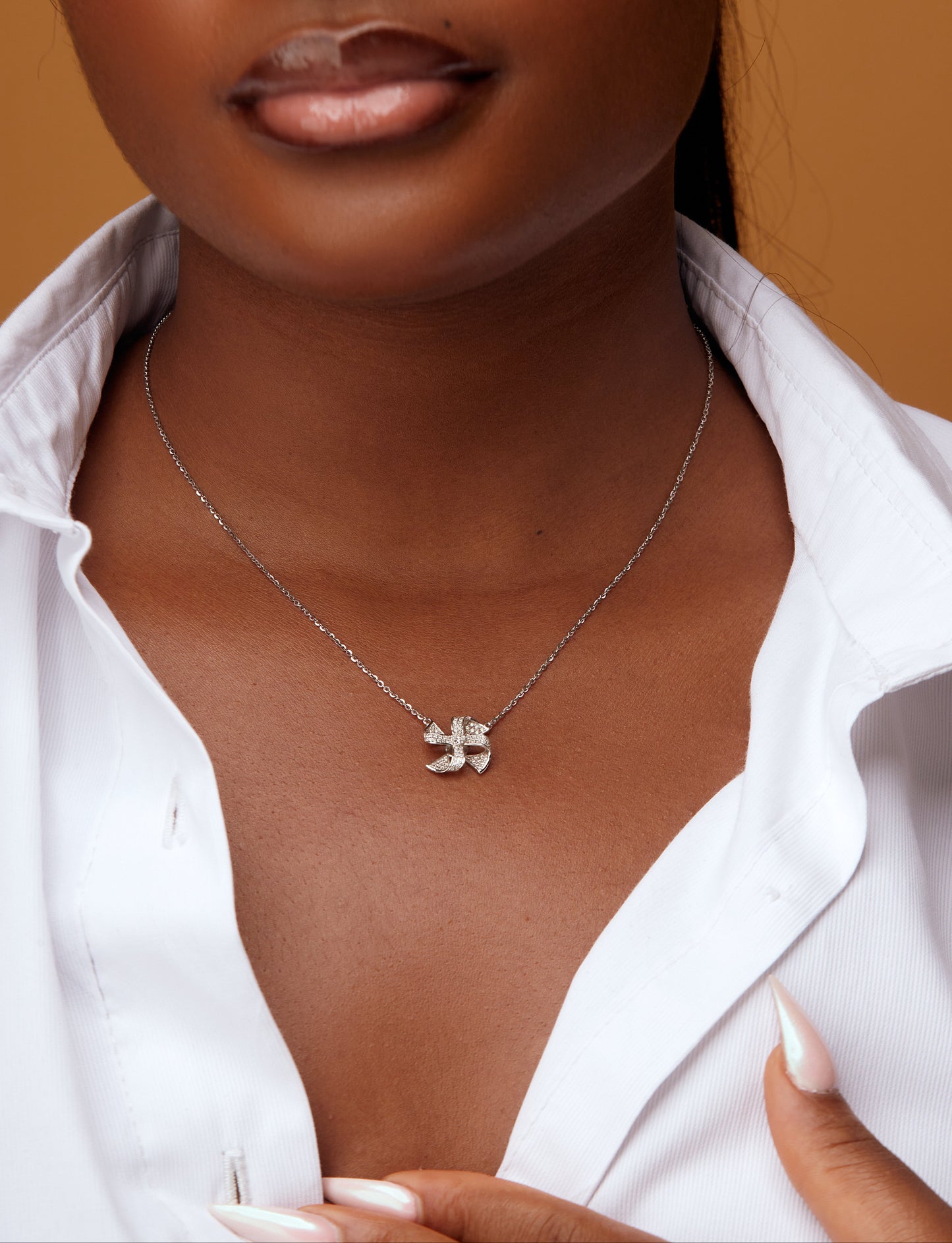 Woman wearing a silver necklace with a small pendant against a neutral background