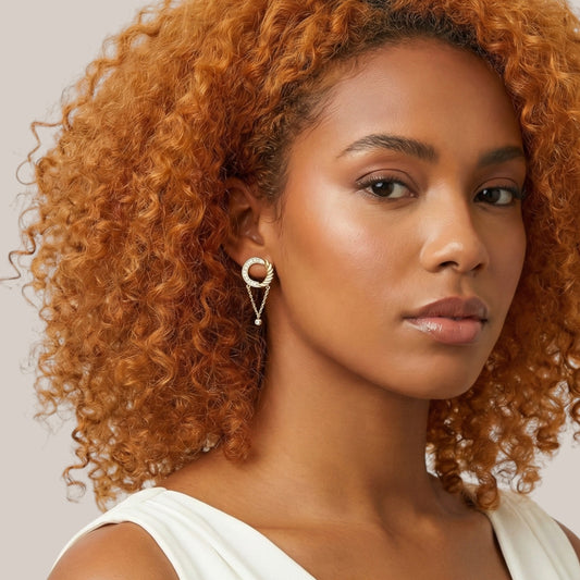 Woman with curly orange hair wearing a white top against a neutral background