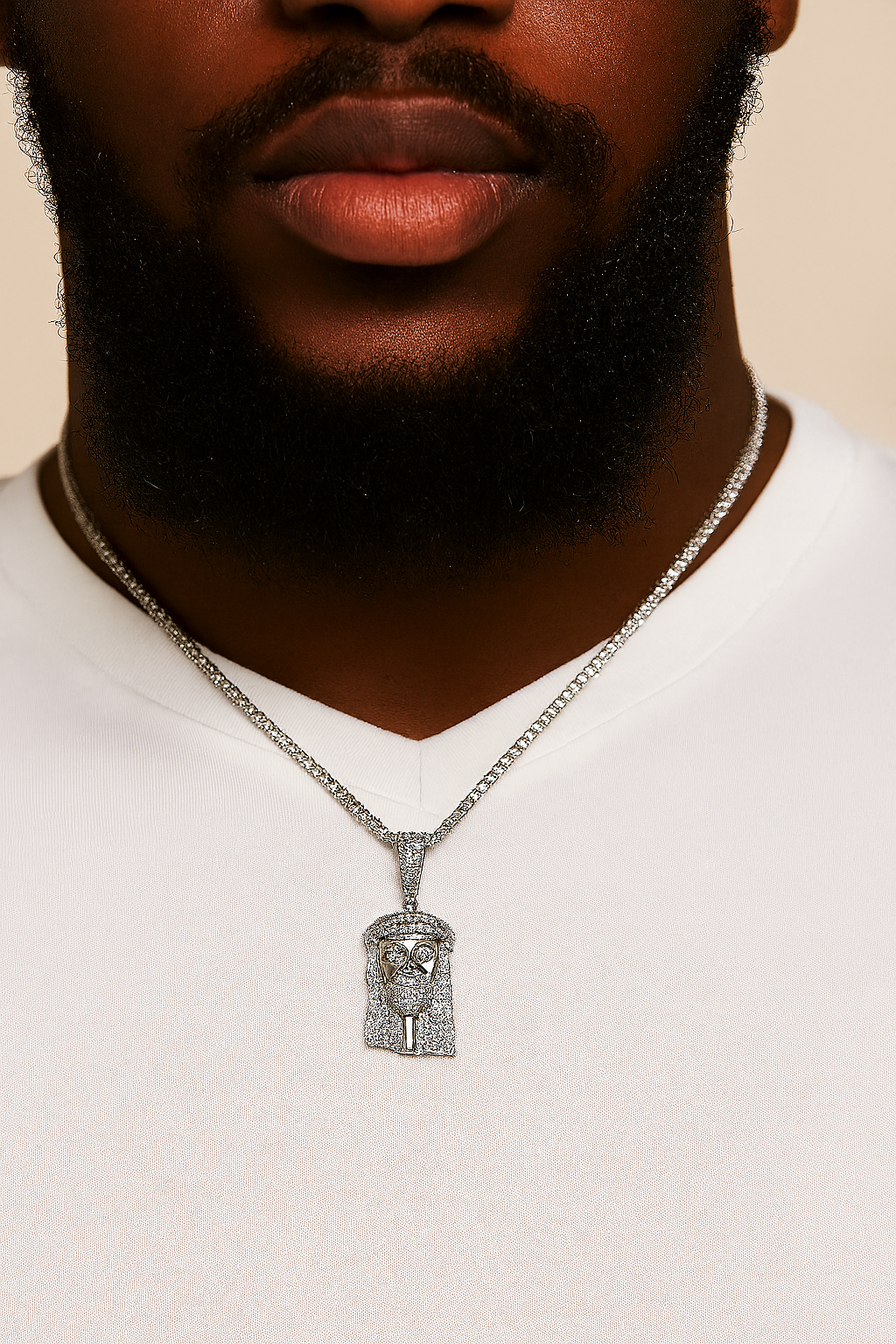 Man wearing a white shirt with a silver necklace featuring a detailed pendant against a beige background