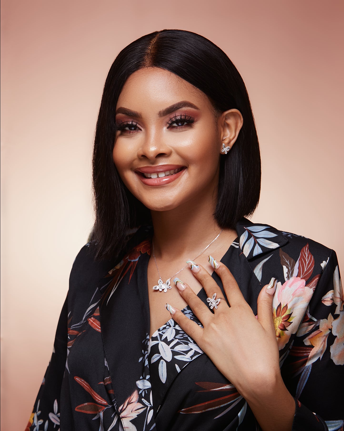 Woman wearing jewelry with a floral patterned outfit against a beige background