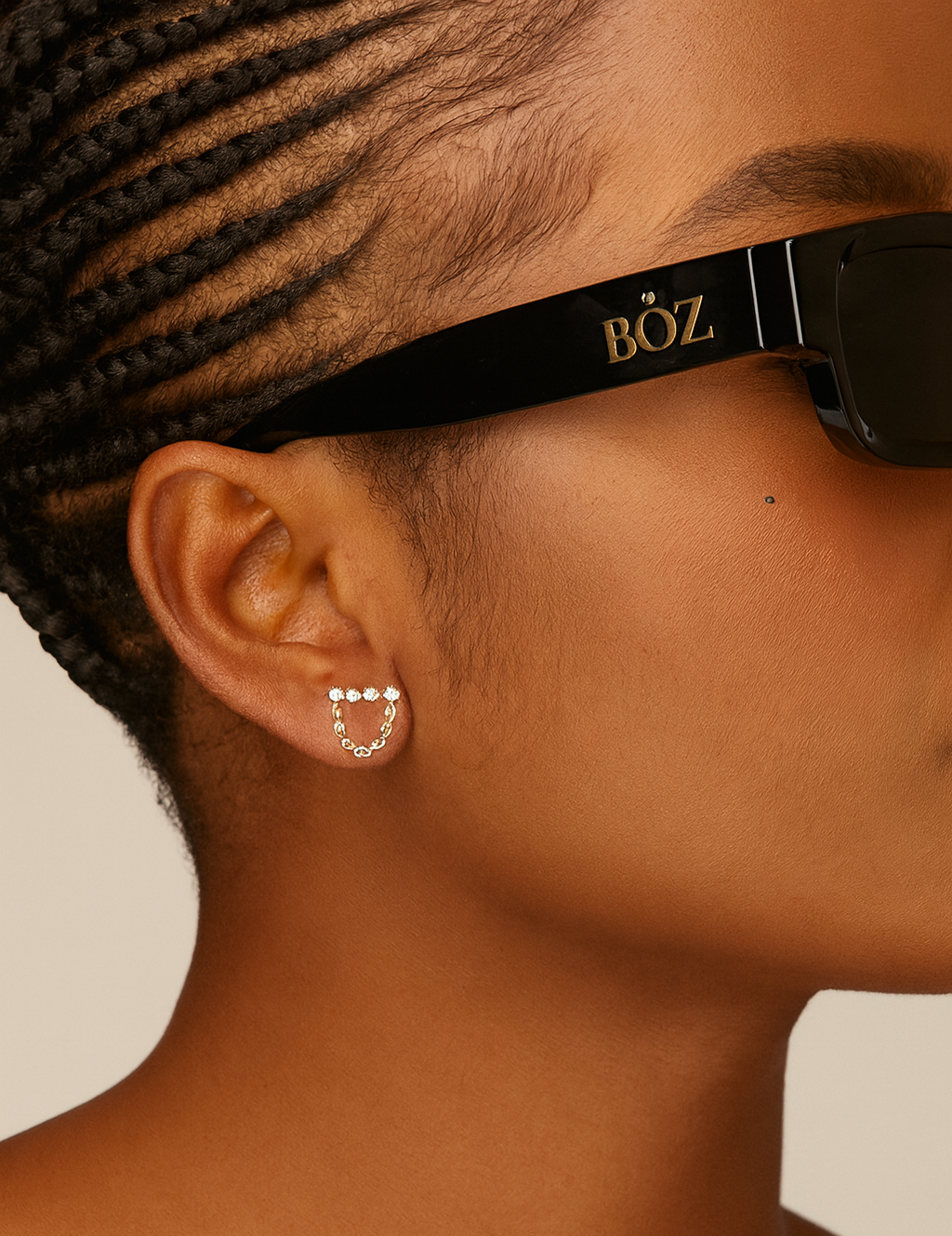 Close-up of a person wearing black sunglasses with 'BOZ' branding, focusing on the ear and neck area.