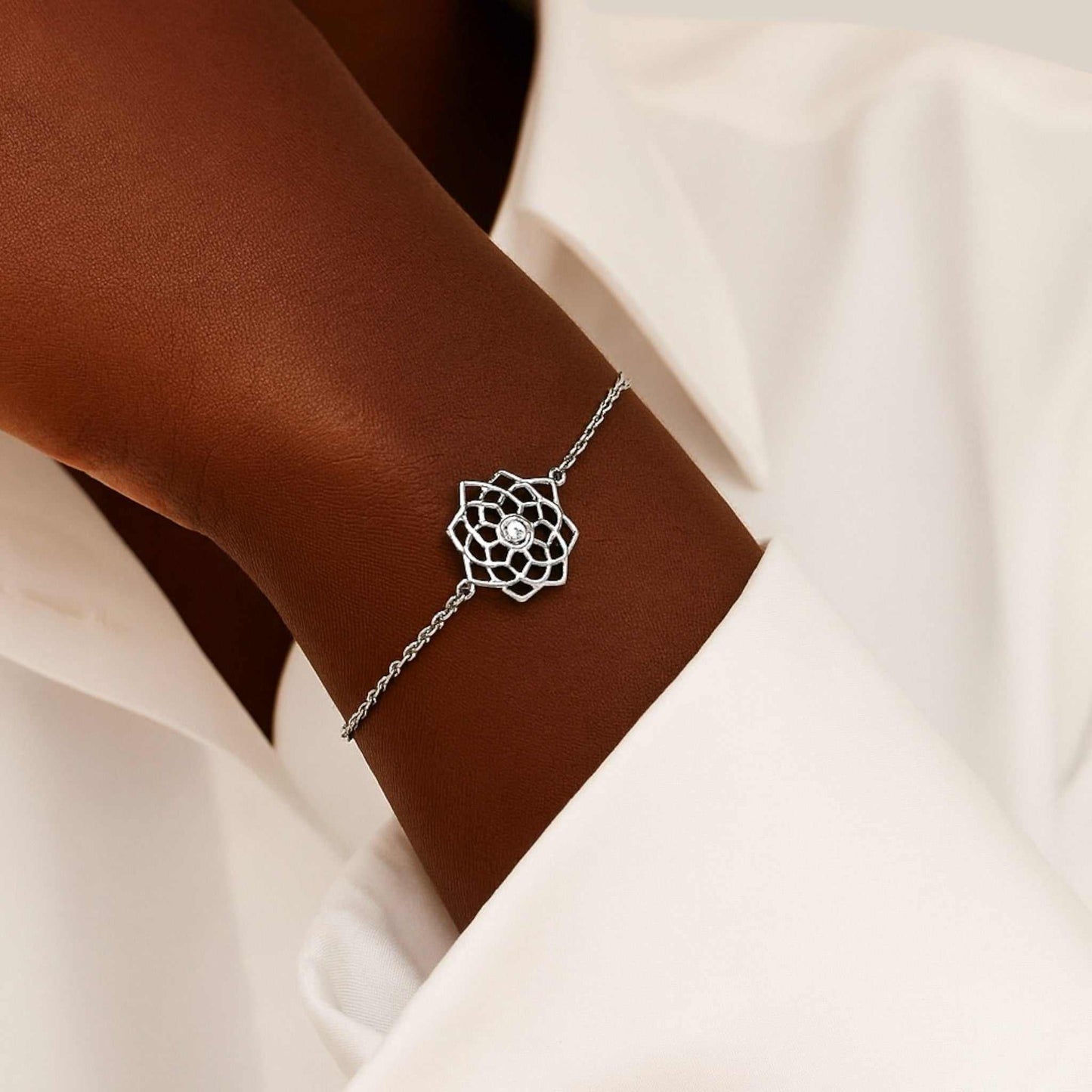 Silver bracelet with a diamond on a wrist against a neutral background