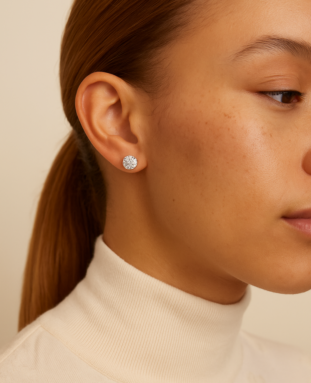 Close-up of a person wearing a silver earring with a beige background