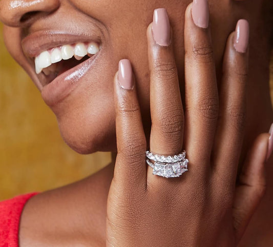A woman is shown wearing a sterling silver engagement ring with a cubic zirconia gemstone on her finger.