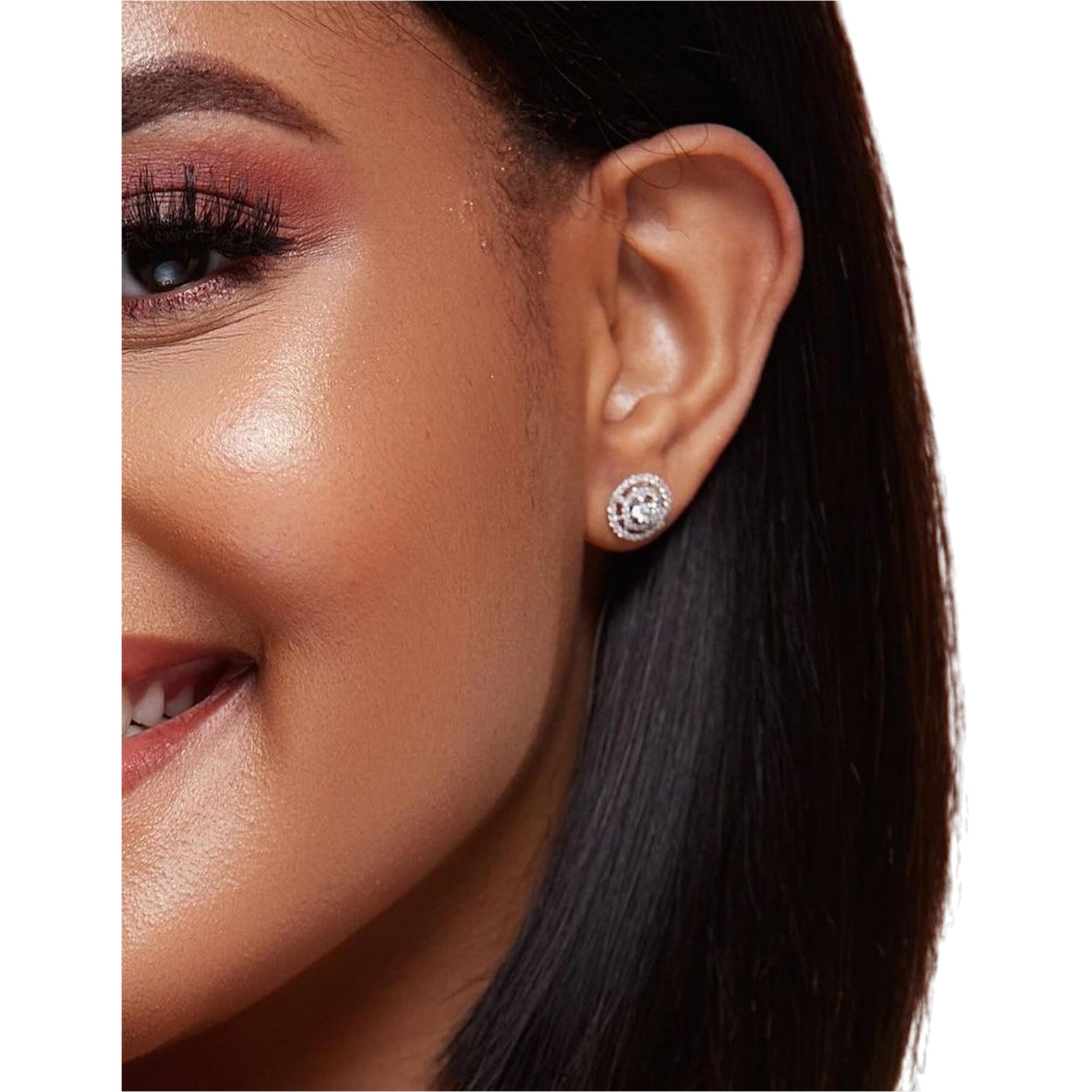 Close-up of a woman wearing a diamond stud earring on a white background