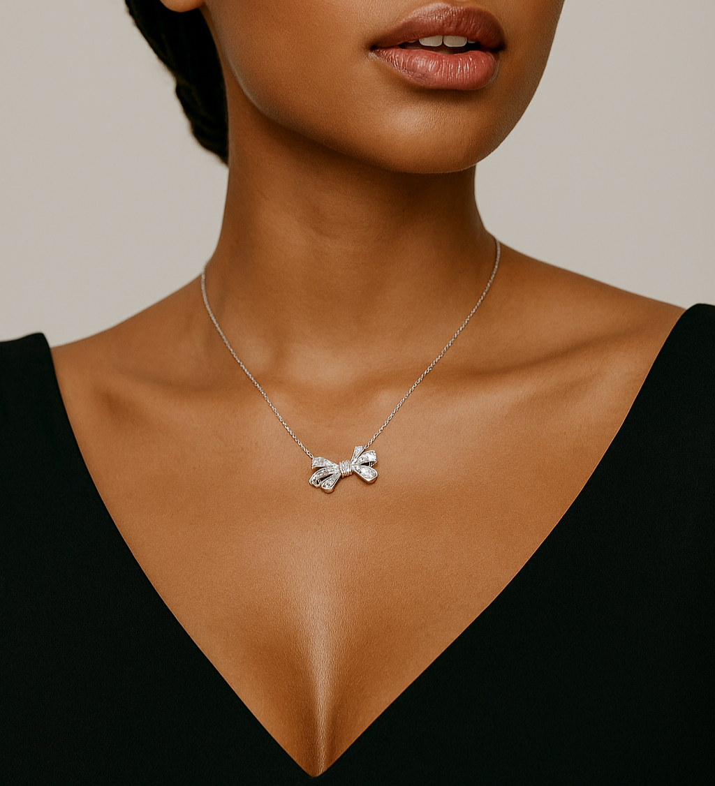 Woman wearing a silver necklace with a bow pendant against a neutral background