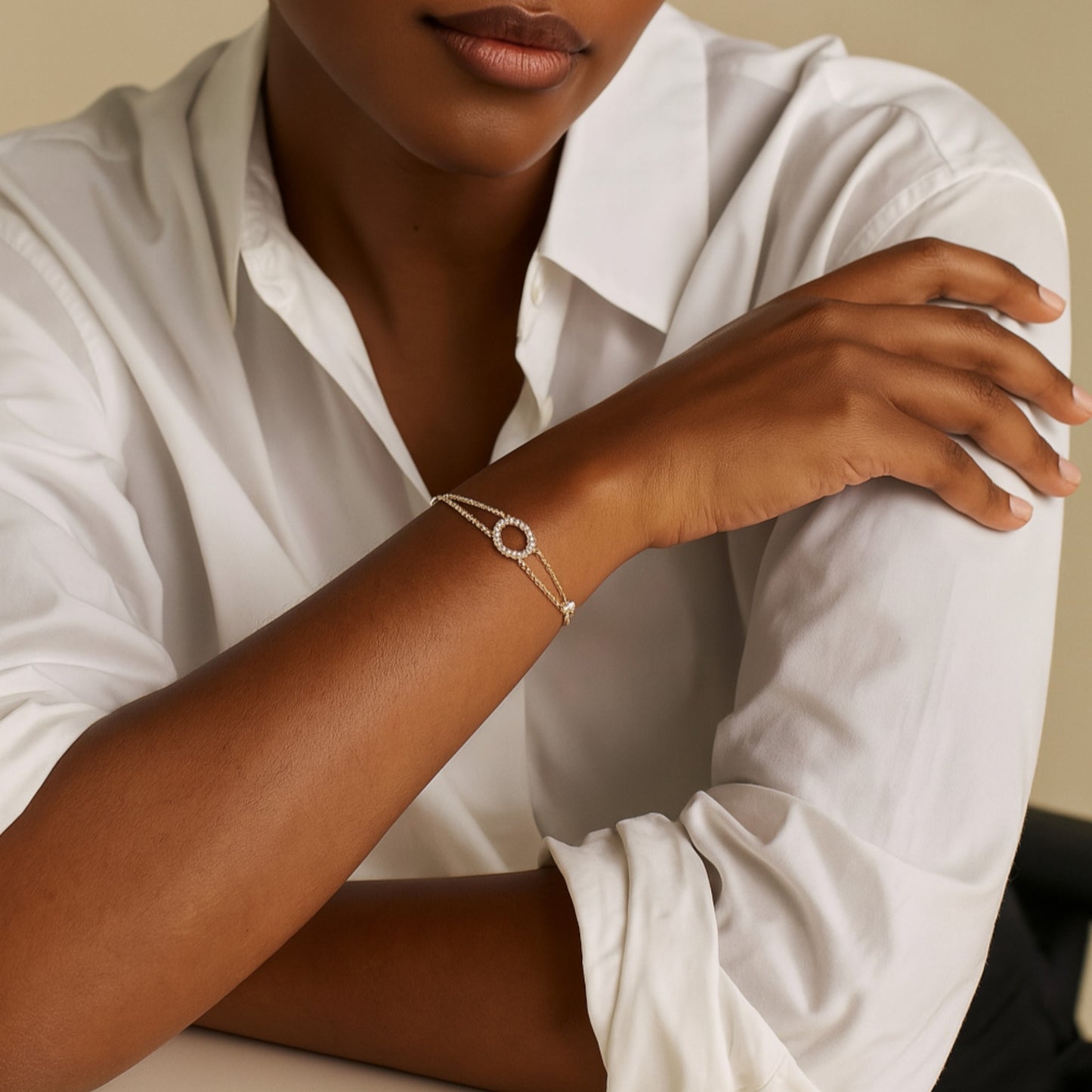 Person wearing a gold bracelet with a circular design on a neutral background