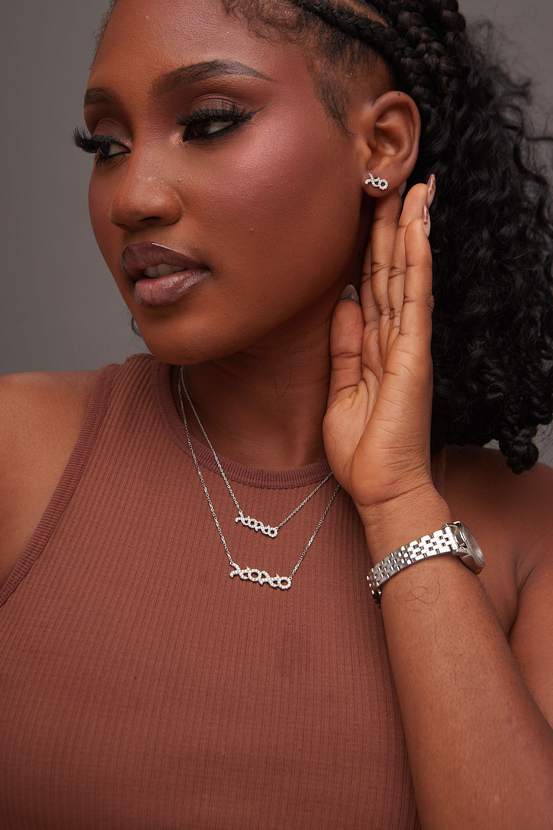 Woman wearing silver jewelry including earrings, necklace, and bracelet against a neutral background