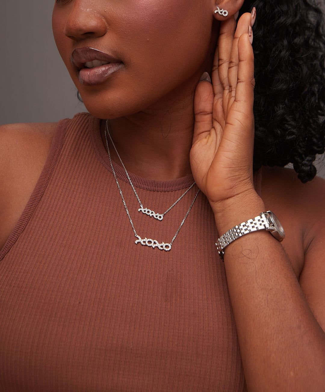 Woman wearing silver jewelry including earrings, necklace, and bracelet against a neutral background