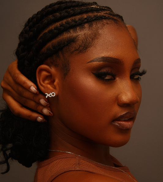 Woman with braided hair wearing a brown top against a neutral background