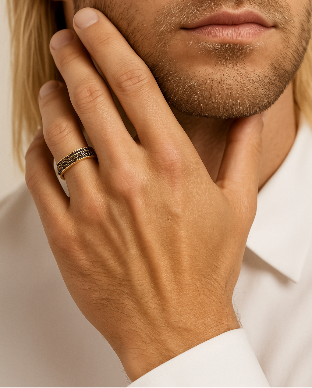 Close-up of a man's hand with a ring on his finger, touching his face.