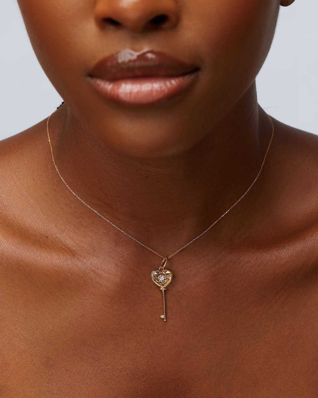 This image features an elegant Heart Key Diamond Necklace crafted in 18K gold. The necklace is graced with a delicate chain that enhances the sophisticated appeal of the heart-shaped key pendant, which is adorned with a sparkling diamond.