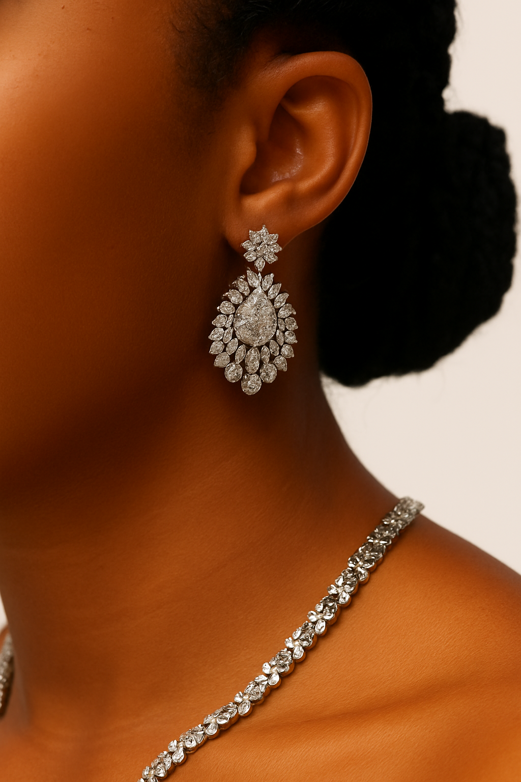 Close-up of a person wearing sparkling silver earrings and a matching necklace.