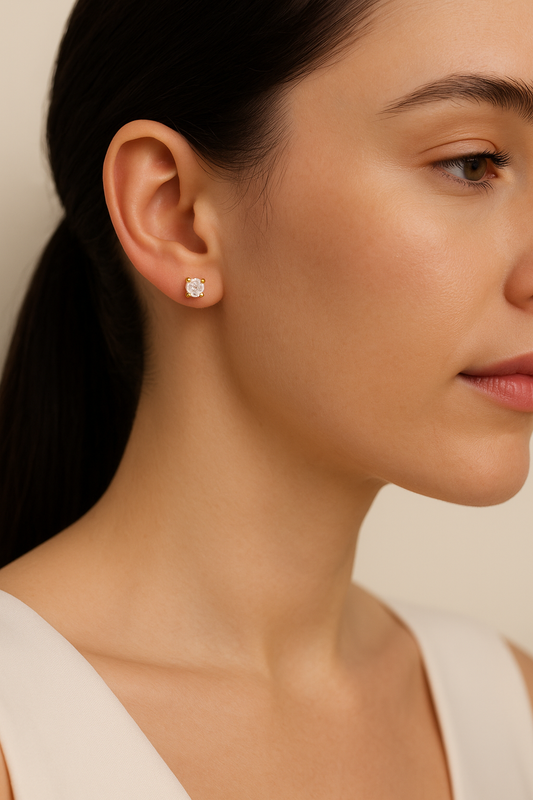 Close-up of a woman wearing diamond stud earrings with a neutral background