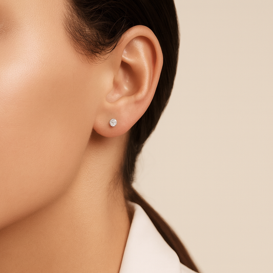 Close-up of an ear wearing a diamond stud earring on a neutral background