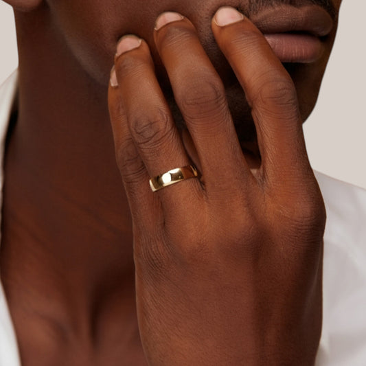 Hand wearing a gold ring with a neutral background