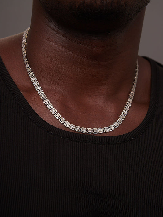 Person wearing a diamond necklace against a dark background