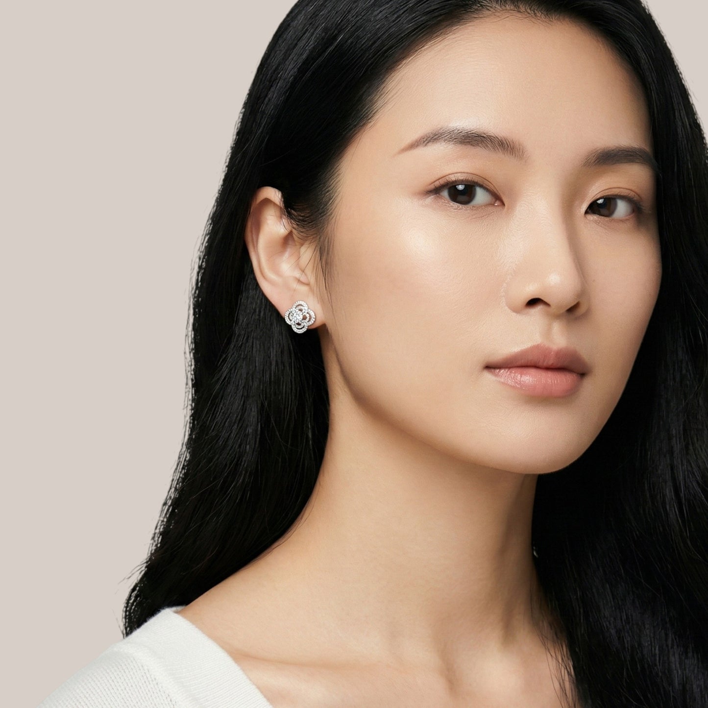 Woman wearing diamond earrings against a neutral background