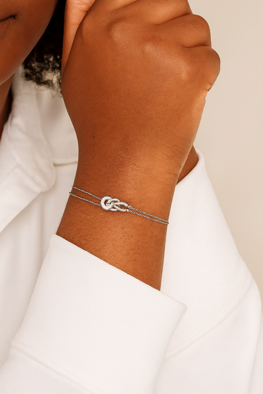 Silver bracelet on a wrist with a plain background