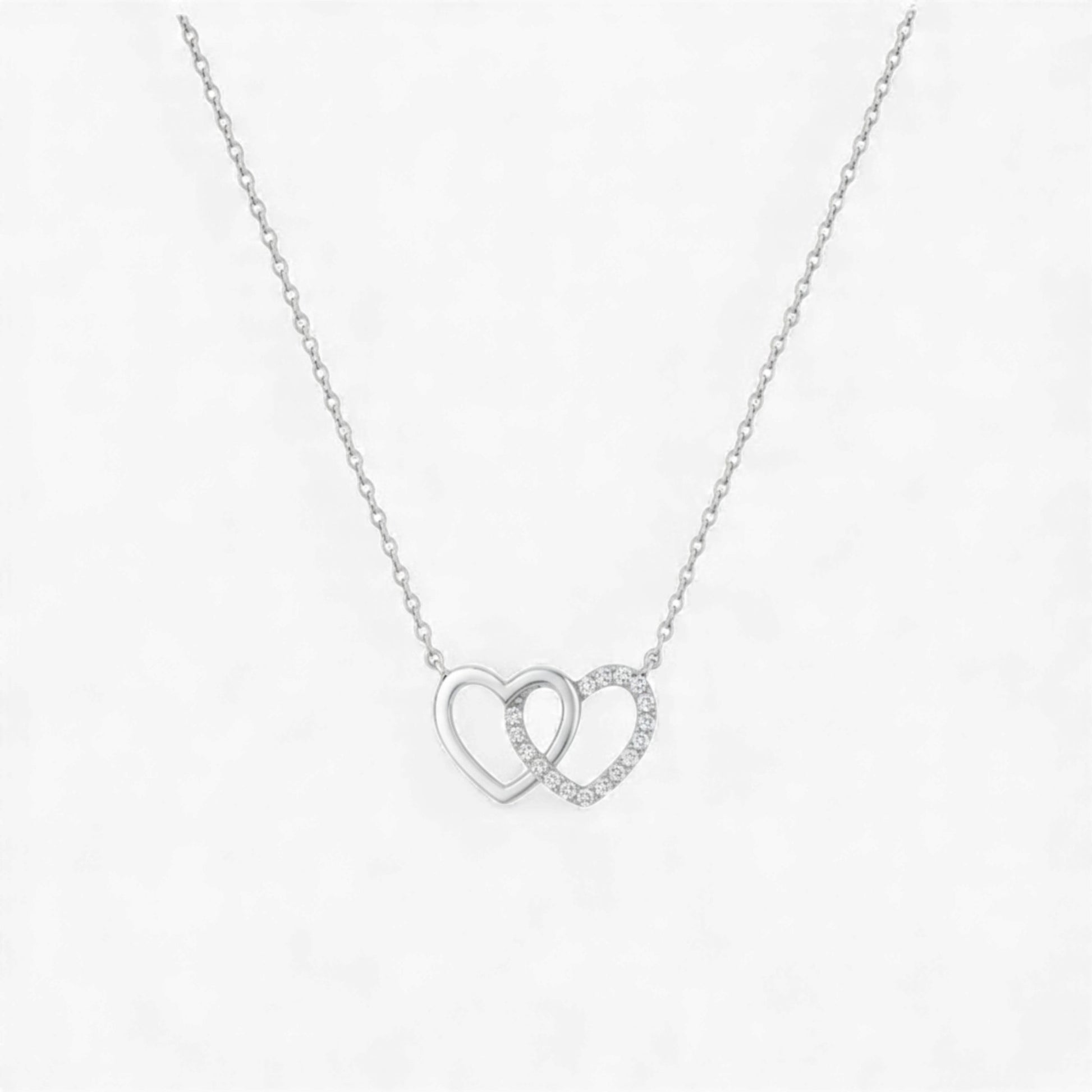 Silver necklace with interlocking heart pendants on a white background