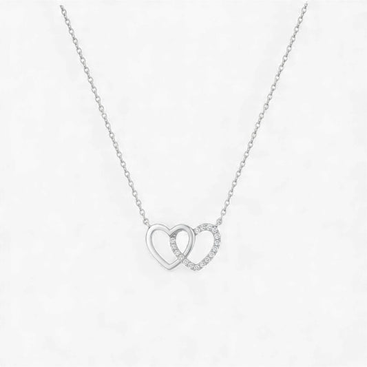 Silver necklace with interlocking heart pendants on a white background