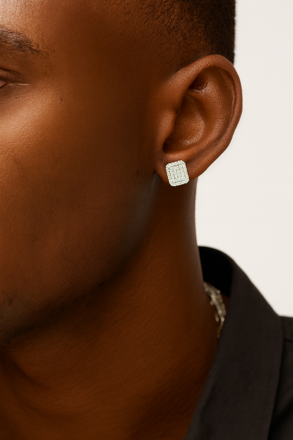 Close-up of a person wearing a silver earring on a neutral background